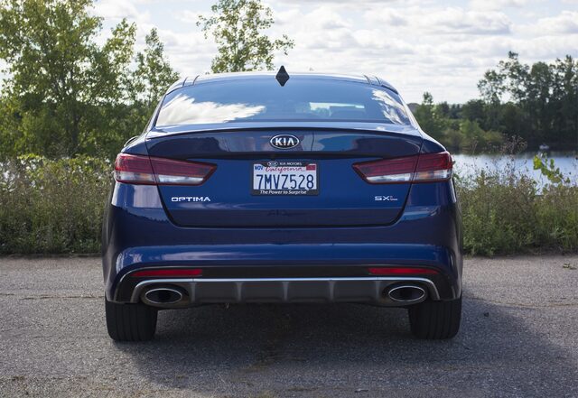 2016 Kia Optima SXL Straight Rear View with SXL Badge and Dual Exhaust Outlets Near Lake