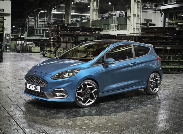 2018 Ford Fiesta ST blue hatchback front three-quarter view inside factory with wet floor