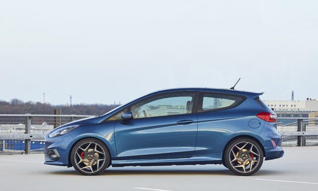 2018 Ford Fiesta ST blue hatchback side profile on rooftop parking deck with gold wheels