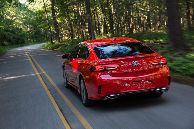 2018 Buick Regal GS, rear three-quarter view with dual exhaust on a wooded road