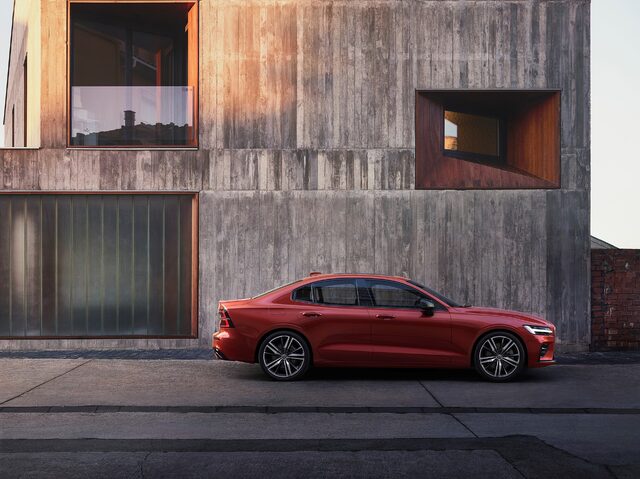 2019 Volvo S60 R-Design side profile in Fusion Red against urban architecture