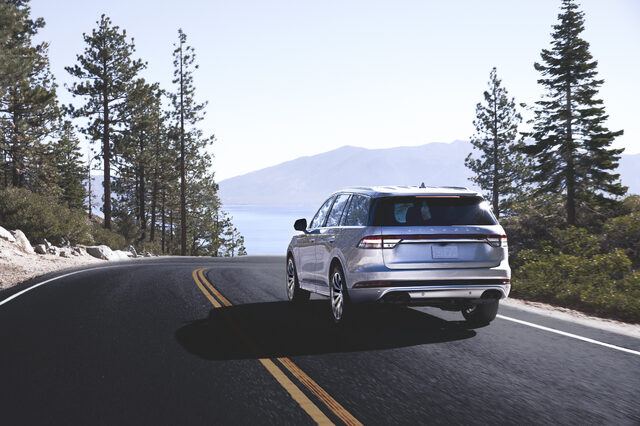 2020 Lincoln Aviator Grand Touring, rear three-quarter action shot on lakeside road