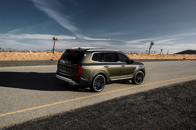 2020 Kia Telluride EX rear three-quarter view on desert highway in dark olive