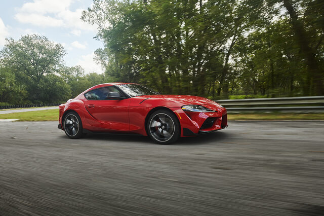 2020 Toyota GR Supra red front three-quarter panning shot on track with trees