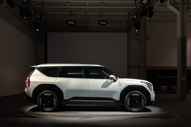 2024 Kia EV9 side profile view on a darkened reveal stage, showing the flat polygonal body lines and three-row proportions