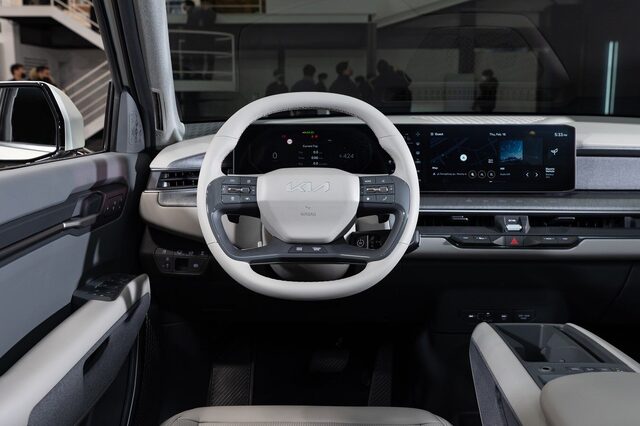 2024 Kia EV9 driver's cockpit view showing the Kia steering wheel and dual widescreen infotainment and instrument displays