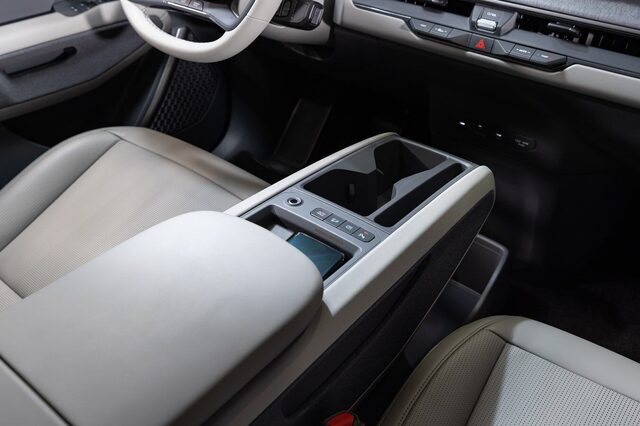 2024 Kia EV9 center console close-up showing the floating armrest storage unit with wireless charging pad and climate controls