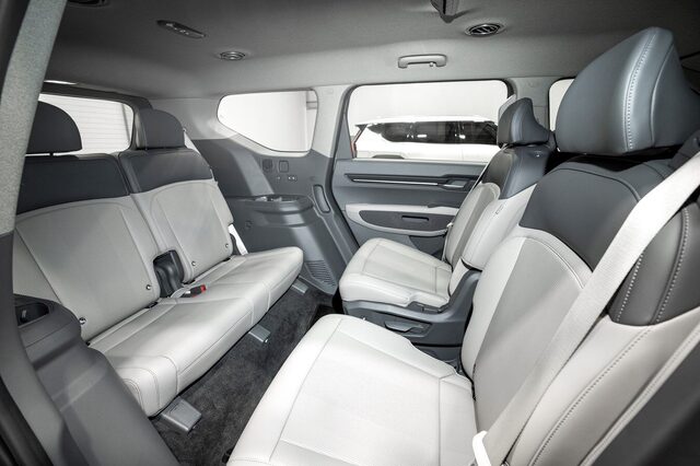 2024 Kia EV9 multi-row interior view showing second and third-row seating with light gray leather in a seven-seat configuration