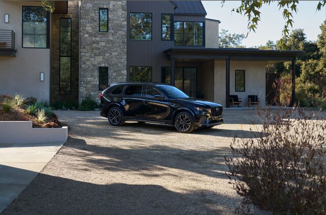 2025 Mazda CX-70 front three-quarter view parked at modern home