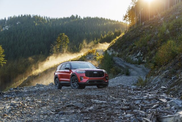 2025 Ford Explorer ST in red driving on a dusty gravel mountain road