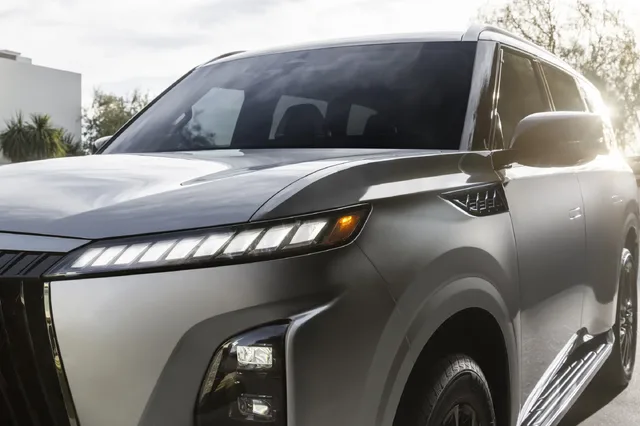 2025 Infiniti QX80 front quarter close-up with headlights on