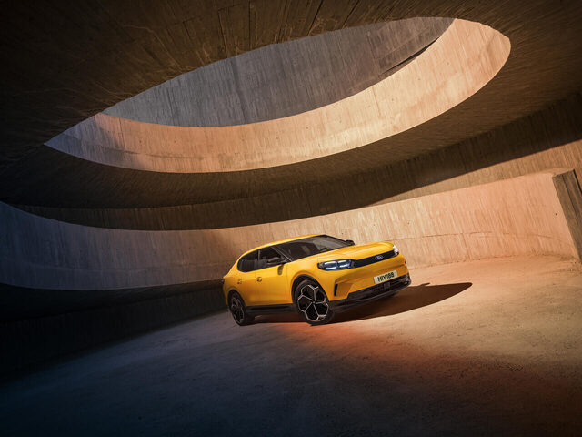 2024 Ford Capri front three-quarter in Vivid Yellow inside concrete architecture