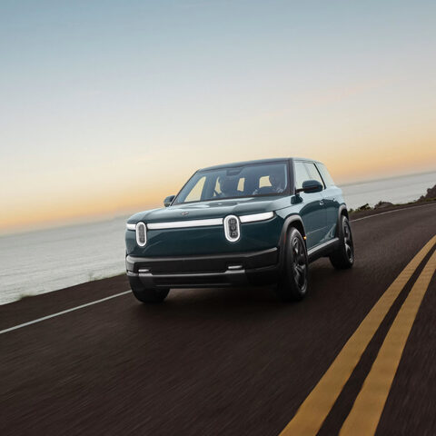 2027 Rivian R2 Front View Driving at Sunset on Coastal Highway